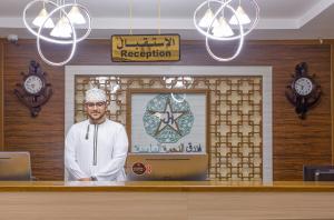 a man standing behind a counter in a restaurant at Diamond Star Hotel فندق النجمة الماسية in Seeb