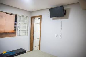 ein Zimmer mit einem Fernseher an der Wand und einem Fenster in der Unterkunft Rancho Recanto Feliz Lindomar Gonçalves Capitólio MG in Capitólio