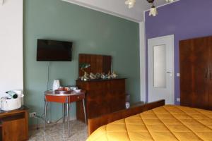 1 dormitorio con cama, mesa y TV en Casa di Nonna Signorina en Giarre