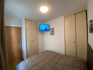 1 dormitorio con 1 cama y TV en la pared en Appartement hyper-centre Loudenvielle 6personnes Jardin proche Balnéa et Skywall en Loudenvielle