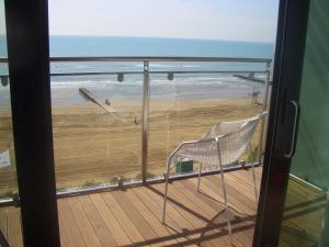 a chair on a balcony with a view of the beach at Hotel Cesare Augustus in Lido di Jesolo