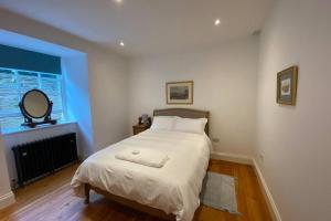 a bedroom with a white bed with a mirror and a window at The Courtyard Apartment, Strangford in Strangford