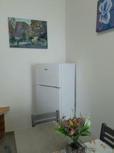 a dining room table with a refrigerator and a vase of flowers at Casa vacanza Viola in Trapani
