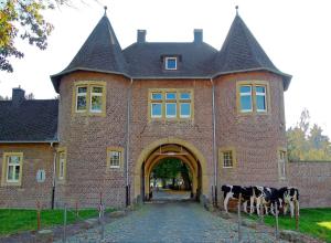 ein Backsteingebäude mit Kühen, die davor stehen in der Unterkunft Vakantiehuis Limburg - Landgraaf in Landgraaf