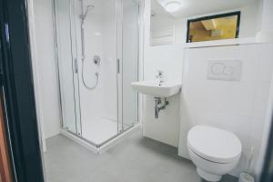 a white bathroom with a toilet and a sink at Vila Šumná in Luhačovice