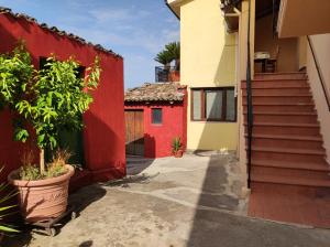 a red and yellow building with stairs and plants at Tana di Zia Nature, Yourself, Love in Viggianello
