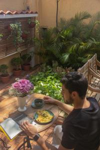 Ein Mann, der an einem Tisch mit einem Teller Essen sitzt. in der Unterkunft Pousada dos Franceses in São Paulo