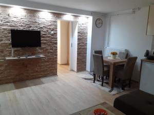 a living room with a table and a television on a brick wall at Apartman Nena in Pirot