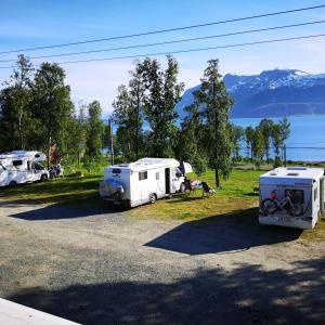 two rvs parked in a field with mountains in the background at Svensby Tursenter in Svensby
