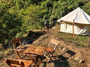 una mesa y sillas frente a una tienda en TRIBE AQUA a nature retreat above Neer waterfall en Rishīkesh