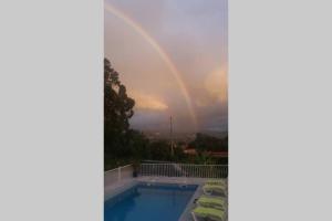 um arco-íris no céu sobre uma piscina em casa das laranjeiras em Abragão
