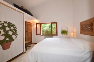a bedroom with a white bed and a window at Villa Giannellina in Orbetello