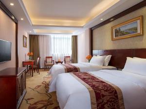 a hotel room with two beds and a television at Vienna Hotel Shenzhen Shiyan Shilong Community in Bao'an