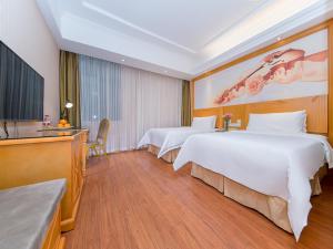 a hotel room with two beds and a television at Vienna Hotel Hubei Xiangyang Tanxi Road in Xiangyang