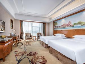 XinyangにあるVienna International Hotel Xinyang Yangshan New Districtのベッド2台が備わる客室で、壁には大きな絵画が飾られています。