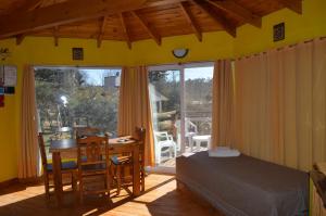 a bedroom with a bed and a desk and a table at Cabañas Kumelkalechi in Los Reartes