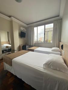 a hotel room with two beds and a window at Hotel Desbravador in Chapecó