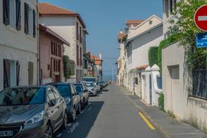 een rij auto's geparkeerd in een straat naast gebouwen bij Appartement lumineux Côte des Basques in Biarritz