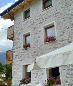 ein Steingebäude mit zwei Fenstern und Blumenkästen in der Unterkunft Antico Melo B&B in Vignole