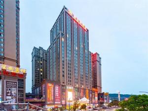 a tall building with lights on it in a city at Vienna Hotel Guizhou Bijie Chuangmei Century City in Bijie