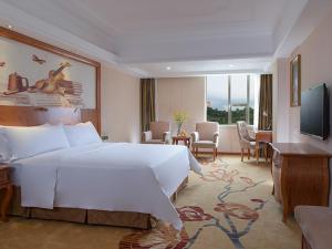 una camera d'albergo con un grande letto bianco e una TV di Vienna International Hotel Shenzhen Caopu Jindaotian a Shenzhen