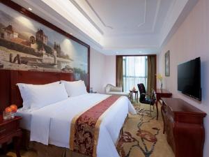 a hotel room with a large bed and a television at Vienna International Hotel Heyuan Yajule Garden in Heyuan