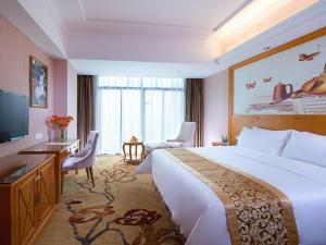 Vienna Hotel Guangdong Huizhou Yuanzhou في Yuanzhou: غرفه فندقيه سرير كبير وتلفزيون