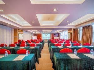 uma sala de conferências com mesas verdes e cadeiras vermelhas em Vienna Hotel Foshan Chancheng Zumiao Branch em Foshan