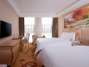 a hotel room with two beds and a flat screen tv at Vienna Hotel (Jieyang Longwei) in Jieyang