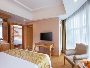 a hotel room with a bed and a desk and a television at Vienna Hotel Guangdong Zhongshan Nanlang in Zhongshan