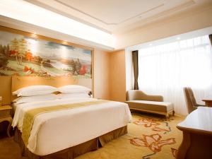 a bedroom with a large bed and a painting on the wall at Vienna International Hotel Hangzhou Xintiandi Yingtai in Hangzhou