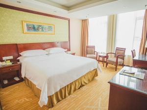 a hotel room with a large bed and a table at Vienna Hotel Dongying Taihangshan Road in Dongying