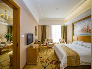 una camera d'albergo con un grande letto e un soggiorno di Vienna Hotel Guizhou Bijie Chuangmei Century City a Bijie