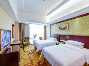 Vienna Hotel Shenzhen Fuyong Qiaotou في باوان: غرفه فندقيه سريرين وتلفزيون