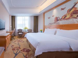 a hotel room with a large bed and a desk at Vienna International Hotel Guangzhou Changlong Qifu Xincun in Guangzhou