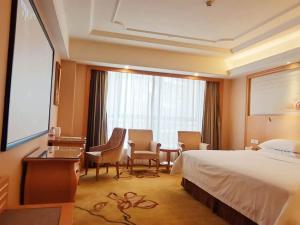 um quarto de hotel com uma cama, uma mesa e cadeiras em Vienna Hotel Shenzhen Xiashuijing Subway Station em Shenzhen