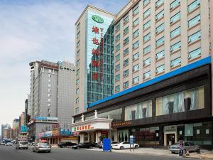 duży budynek z samochodami zaparkowanymi przed nim w obiekcie Vienna Hotel Dongguan Changping Avenue w mieście Dongguan