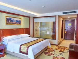 a bedroom with a large bed and a bathroom at Vienna Hotel Shenzhen Shajing Shangnan in Bao'an