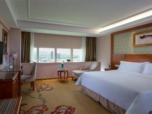 Habitación de hotel con cama blanca grande y escritorio. en Vienna Hotel Mix City en Shenzhen