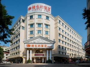 un gran edificio blanco con un cartel. en Vienna Hotel Meizhou Jiangnan, en Meizhou