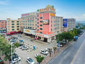 een groot gebouw met auto's geparkeerd op een parkeerplaats bij Vienna Hotel Guangzhou Panyu NanCun in Guangzhou
