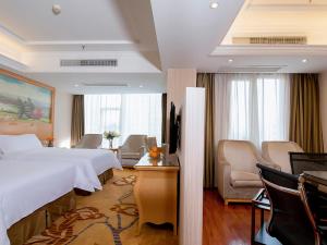 een hotelkamer met een groot bed en stoelen bij Vienna Hotel Jiujiang Railway Station in Jiujiang