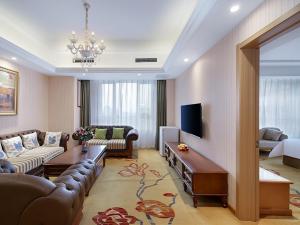XifuにあるVienna Hotel Shandong Qingdao Chengyangのリビングルーム(ソファ、テレビ付)
