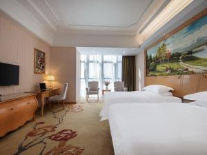 Habitación de hotel con 2 camas, escritorio y TV. en Vienna International Hotel Fuzhou Cangshan Wanda en Fuzhou