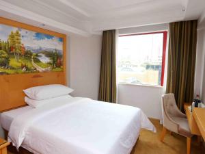 a bedroom with a large white bed and a window at Vienna Hotel Zhongshan West District in Zhongshan