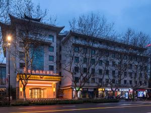 een groot gebouw in een stadsstraat 's nachts bij Vienna International Hotel(Hangzhou Xihu Fengshan Road Station) in Hangzhou