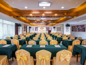 um salão de banquetes com mesas verdes e cadeiras amarelas em Vienna Hotel Xinyu Kaiguang em Xinyu