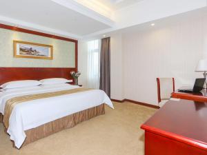 Cette chambre comprend un grand lit et un bureau. dans l'établissement Vienna Hotel Ningbo Ninghai, à Shang-ts'un