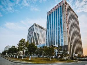 a large tall building with blue windows on a street at Vienna International Hotel Donglin Road in Nanjing