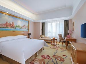 a hotel room with a large bed and a desk at Vienna Hotel Shandong Qingdao Chengyang in Xifu +6 photos
